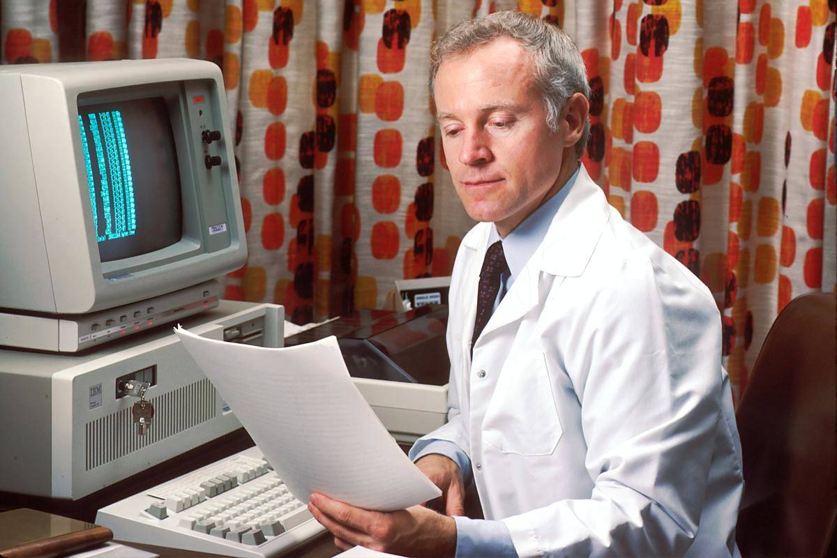 doctor with retro computer looking at paperwork