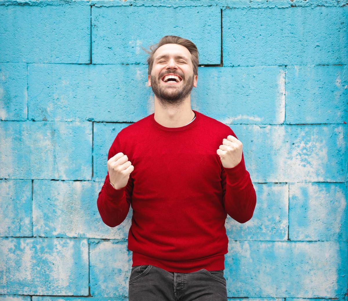 man looks excited standing in front of blue wall