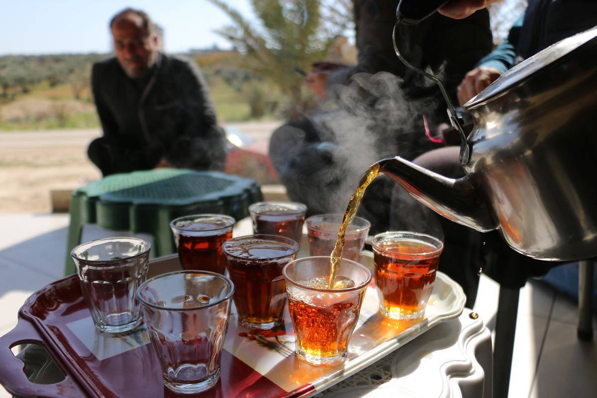 man sits by tray of teas being pourred