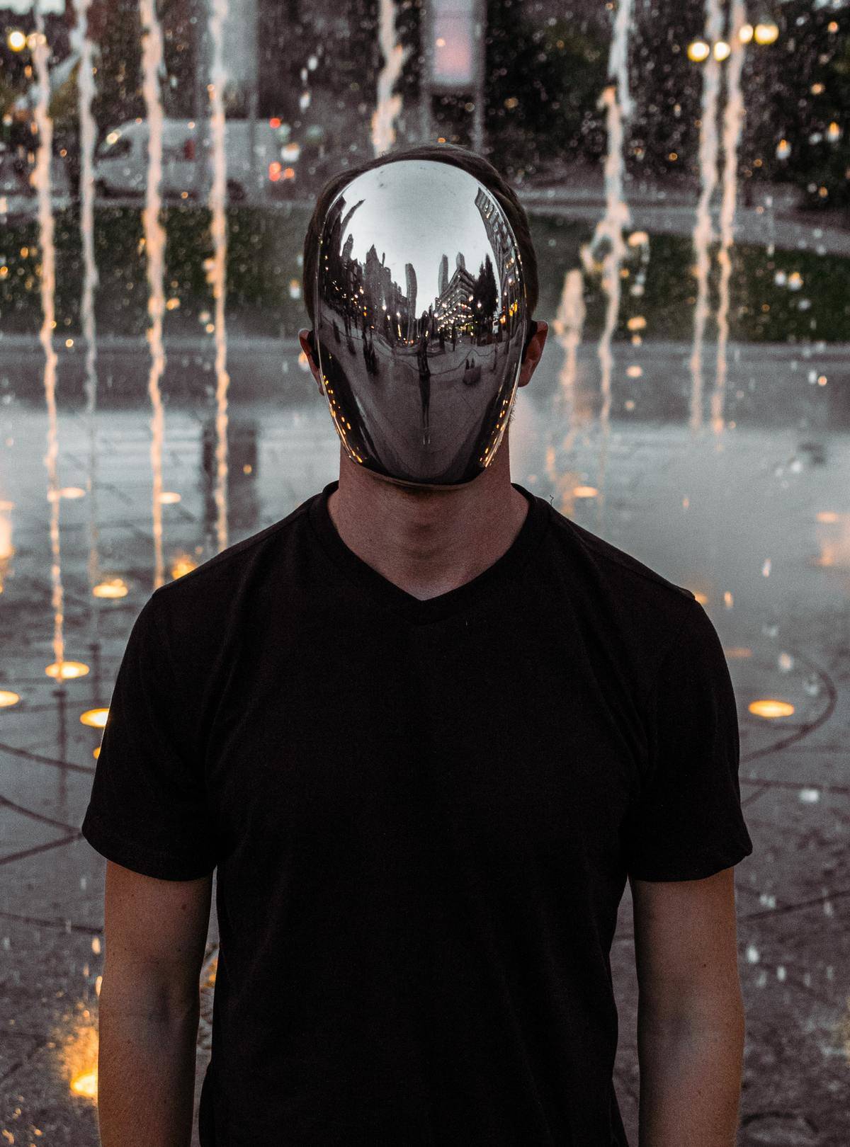 man with reflective face standing in front of a fountain
