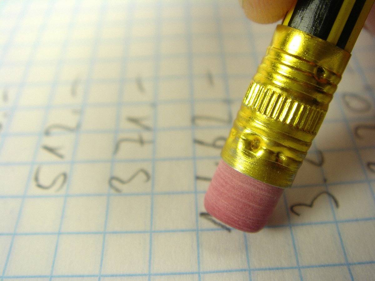 A close-up photo shows someone erasing math problems with a pencil.
