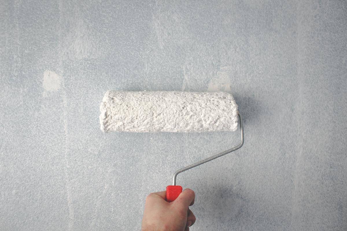 holding paint roller against wall