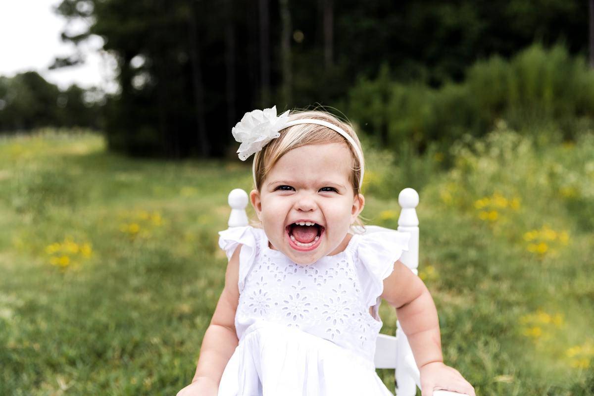 girl in white dress seated smiling yelling