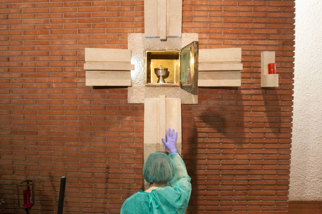 A nurse kneels before the tabernacle