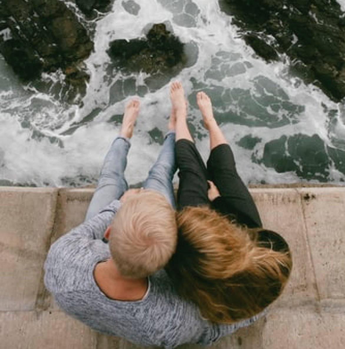couple sitting together with their feet dangling over a body of water