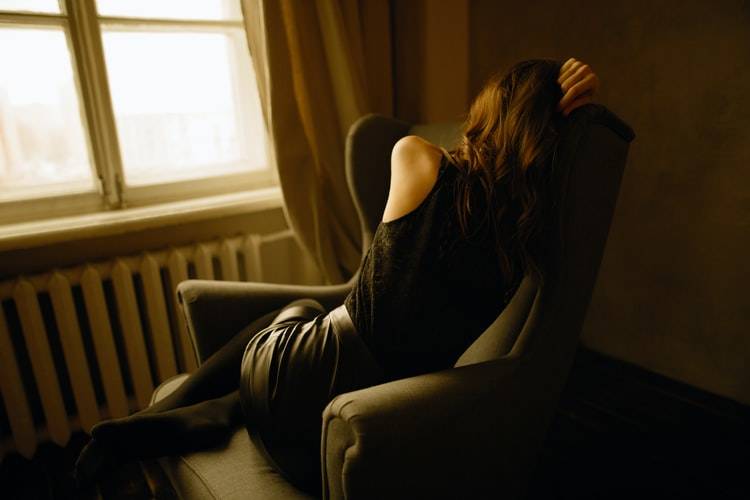 back shot of woman sitting in a chair curled up