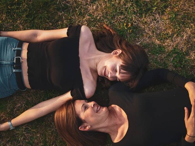 mother and daughter lying on the ground smiling at one another