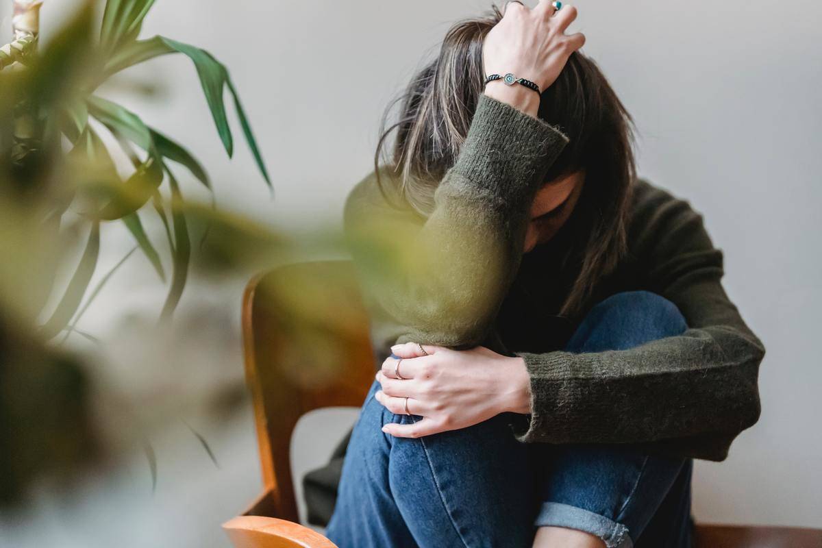 woman in green sweater and jeans curled up on chair