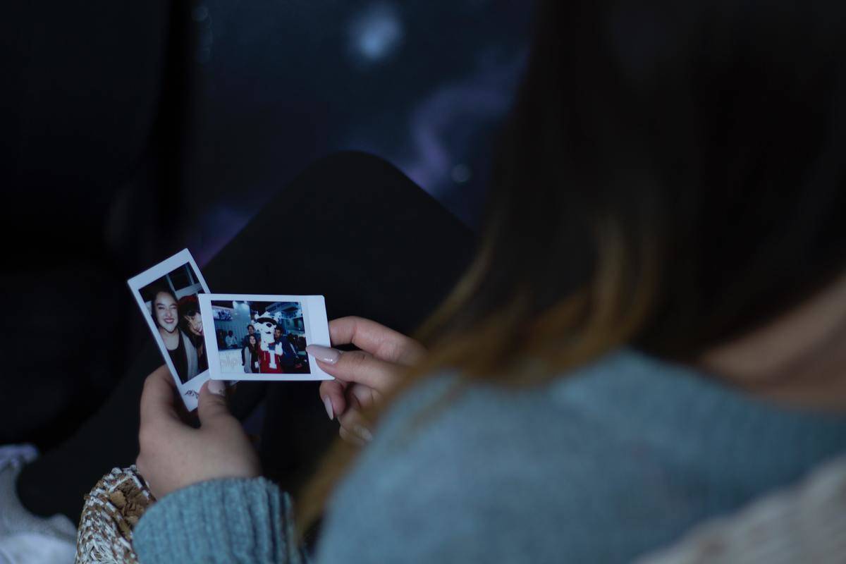 woman looks at polaraid pics in her hand