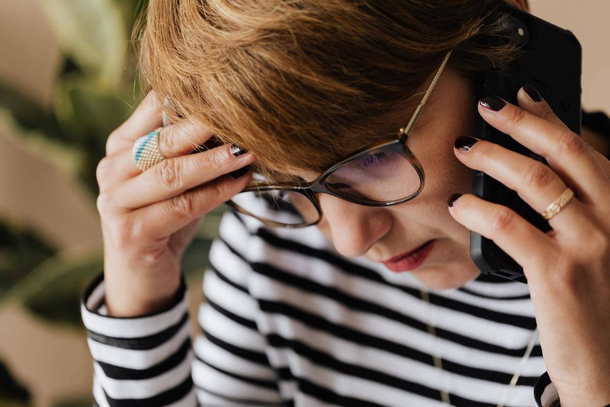 woman in black-and-white striped shirt talking on phone
