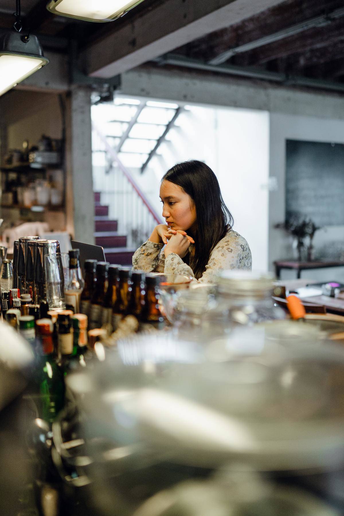 woman sits at a bar looking sad