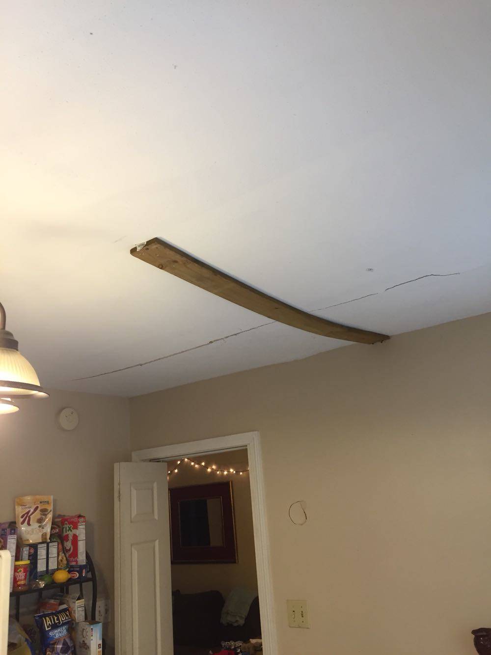 Crack in ceiling temporarily held with a single thin fence board