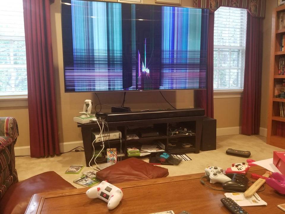 Large TV in living room with screen completely damaged showing lines of color