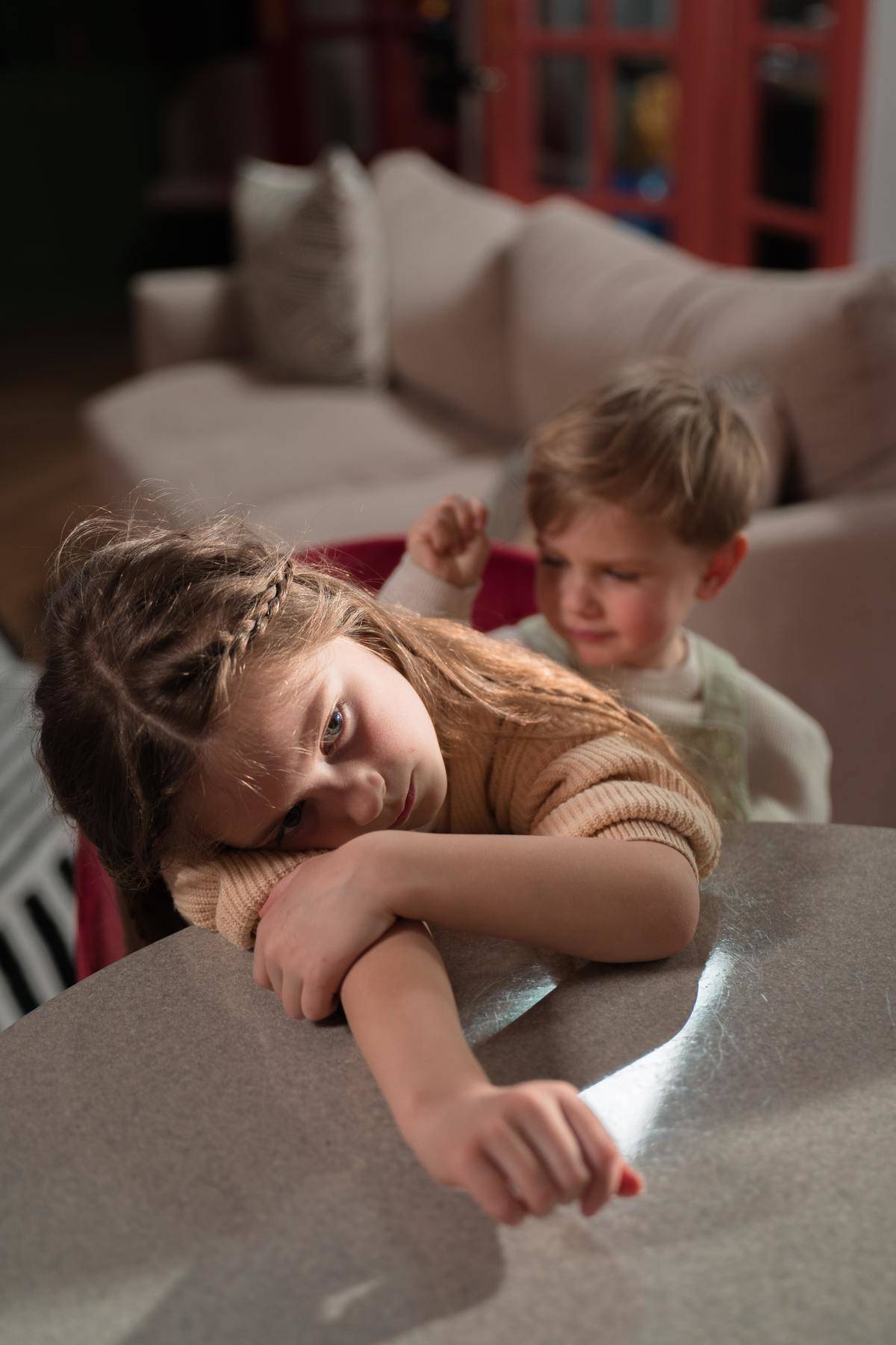 Little girl looks upset while brother is behind her 