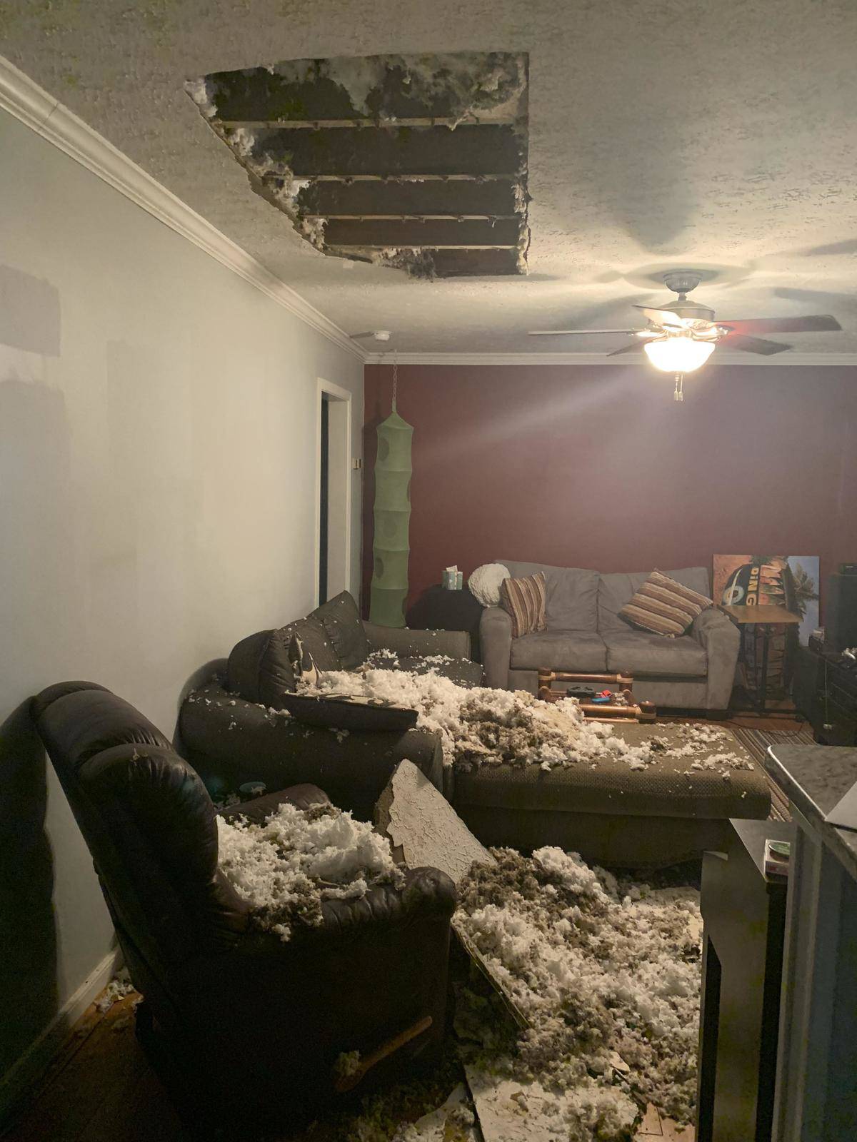 Water-damaged ceiling has dropped the ceiling insulation and tiles all over the living room couch and chair
