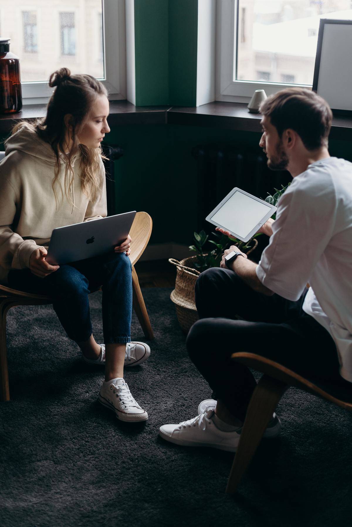 Man and woman sit across from one another, woman on laptop, man on tablet