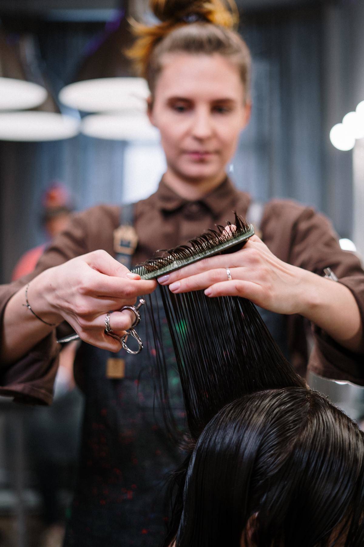 Woman cuts a customer's hair at a salon