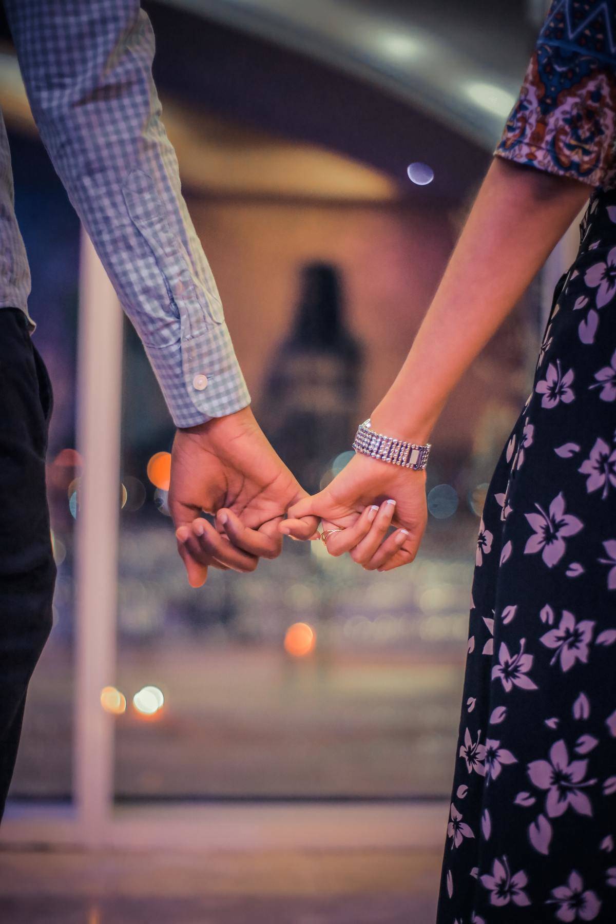 Photo of man and woman holding hands by their pinkies