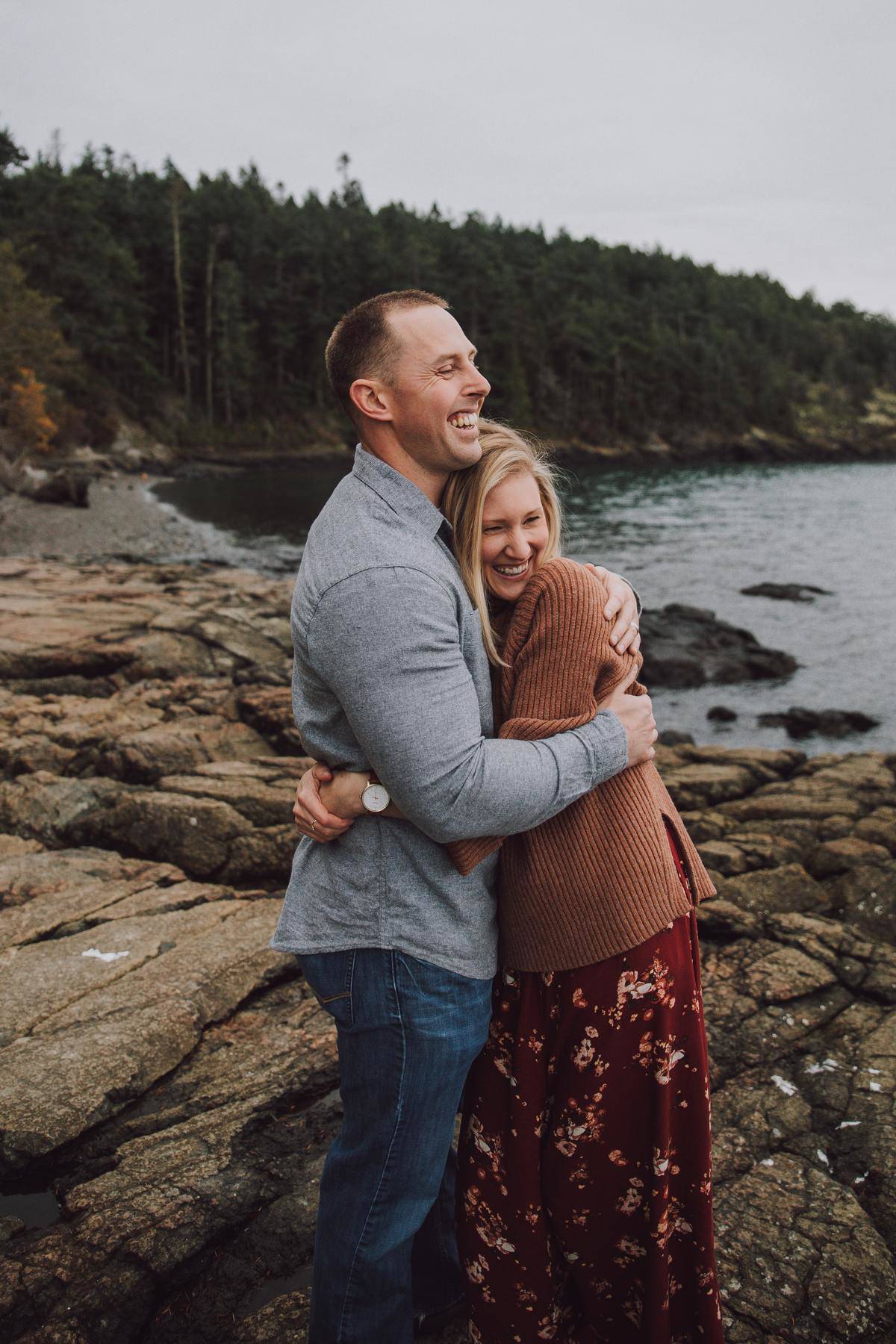 Man and woman hugging outside on rocky beach