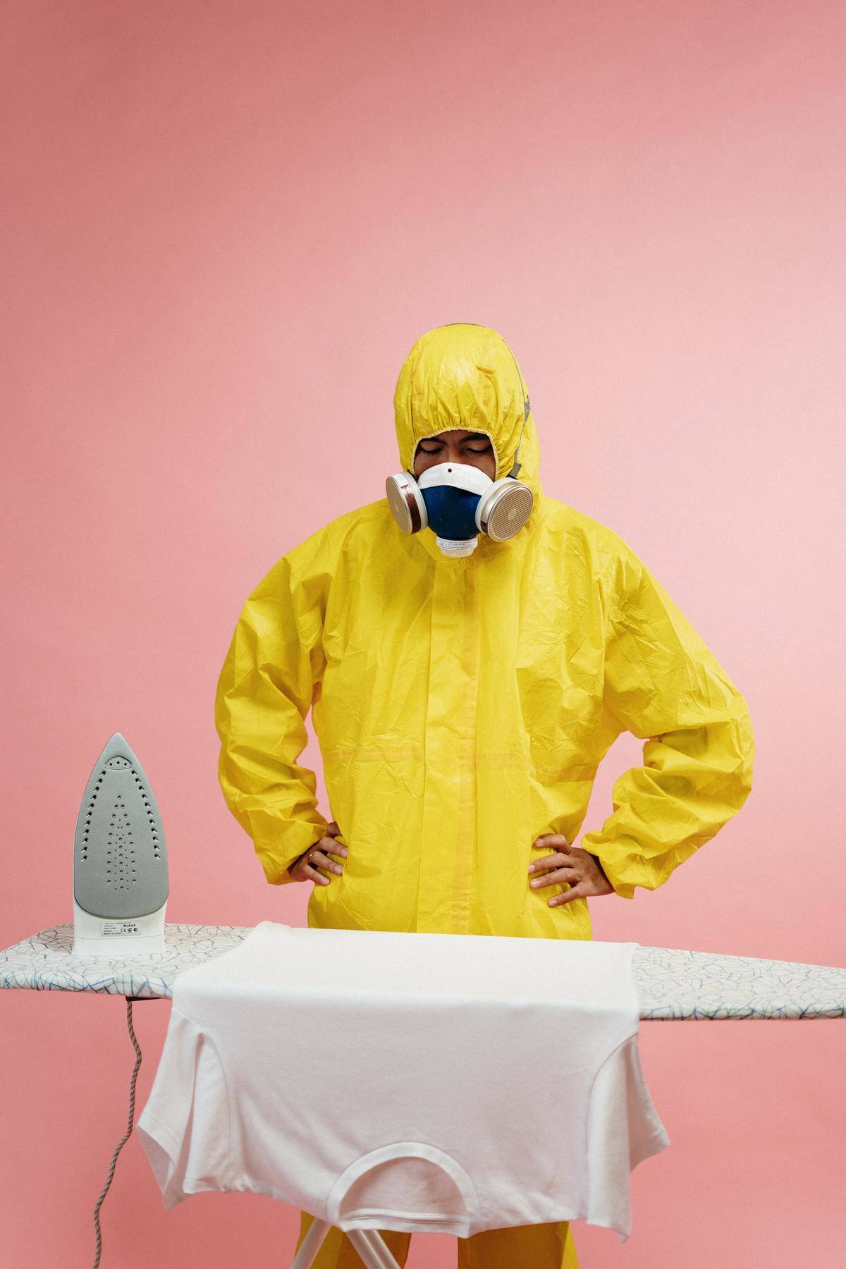 Man wears protective gear and poses with hands on his hips looking at shirt lain across ironing board