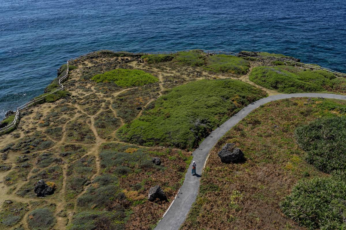 A woman walks along a pathway next to the shoreline on April 30, 2021 in Miyakojima, Japan