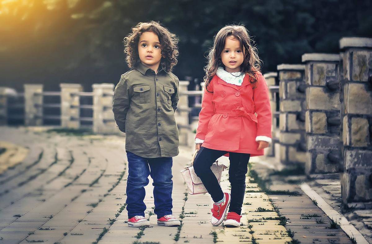 Two small children standing beside each other on a bridge