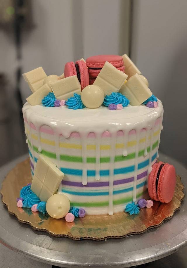 Colorful cake decorated with macarons, white chocolate, and colorful buttercream
