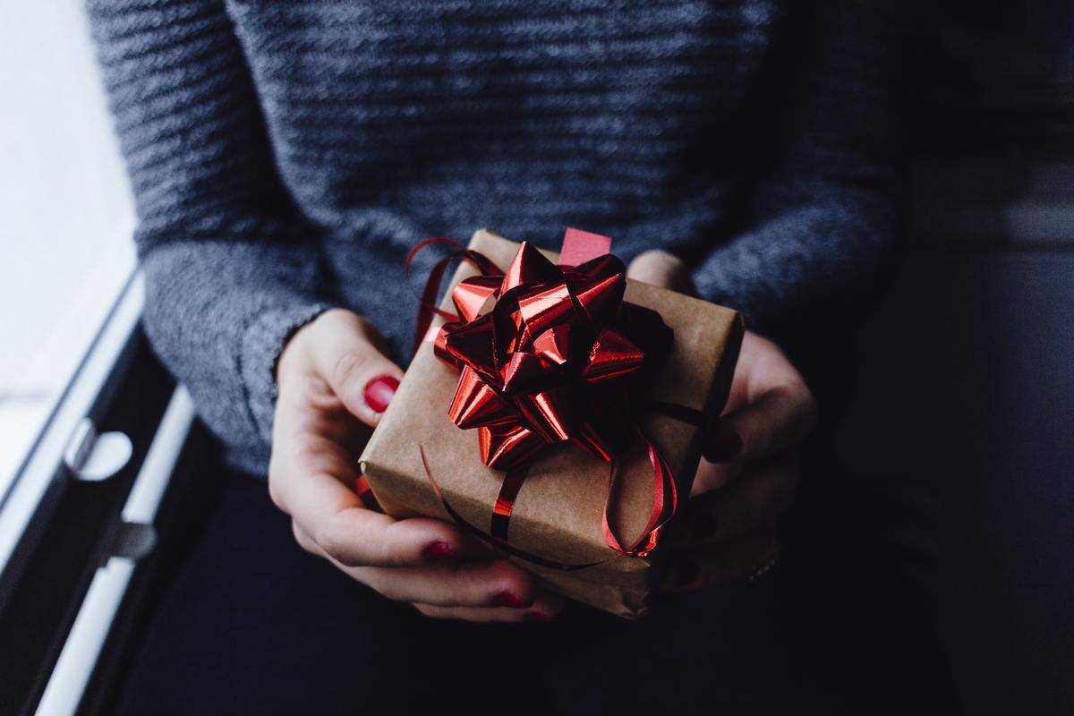 Woman holds present with red bow and ribbon