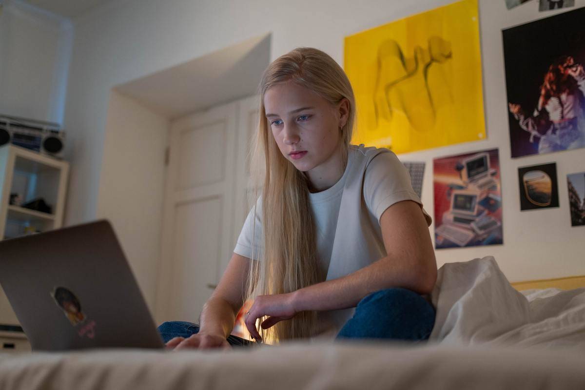 Teenage girl by herself in her bedroom looking at her laptop