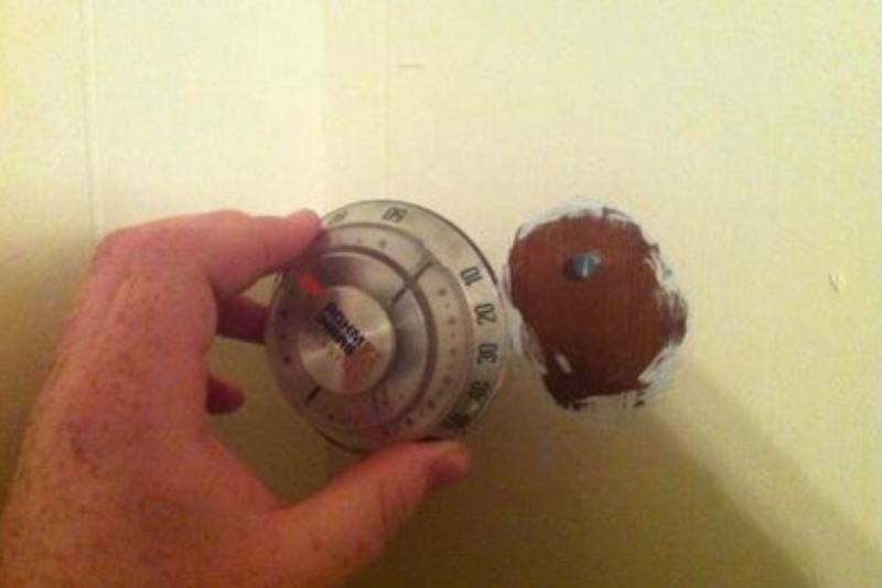 hand holding thermostat that is attached to wall but not wired
