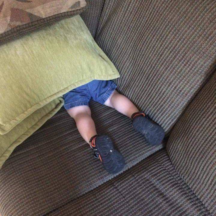 kid hiding under pillow with legs sticking out