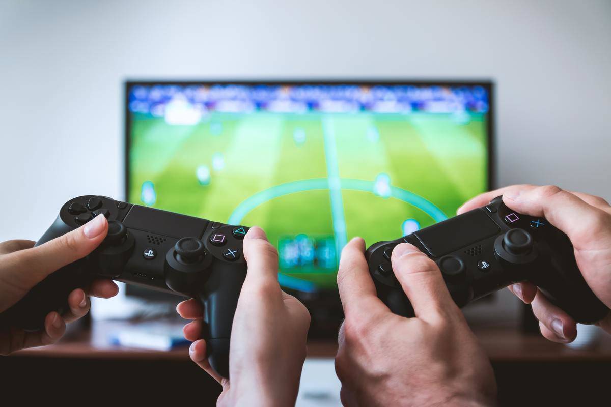 Man and woman playing video games; controllers being held in front of the screen