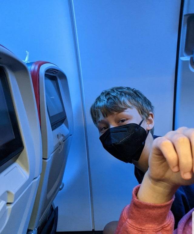 Young boy in an airplane in what should be a window seat, but he has no window
