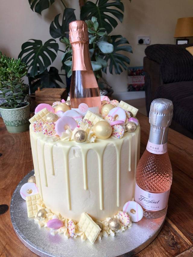 Vanilla cake decorated with white chocolate and mini bottles of wine