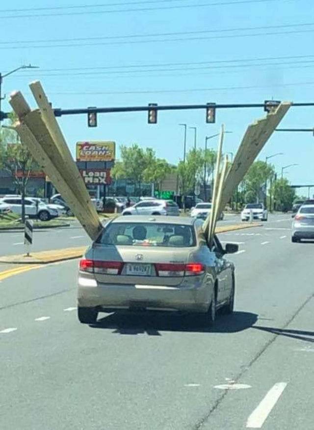 Sedan with massive planks of wood hanging out of the windows