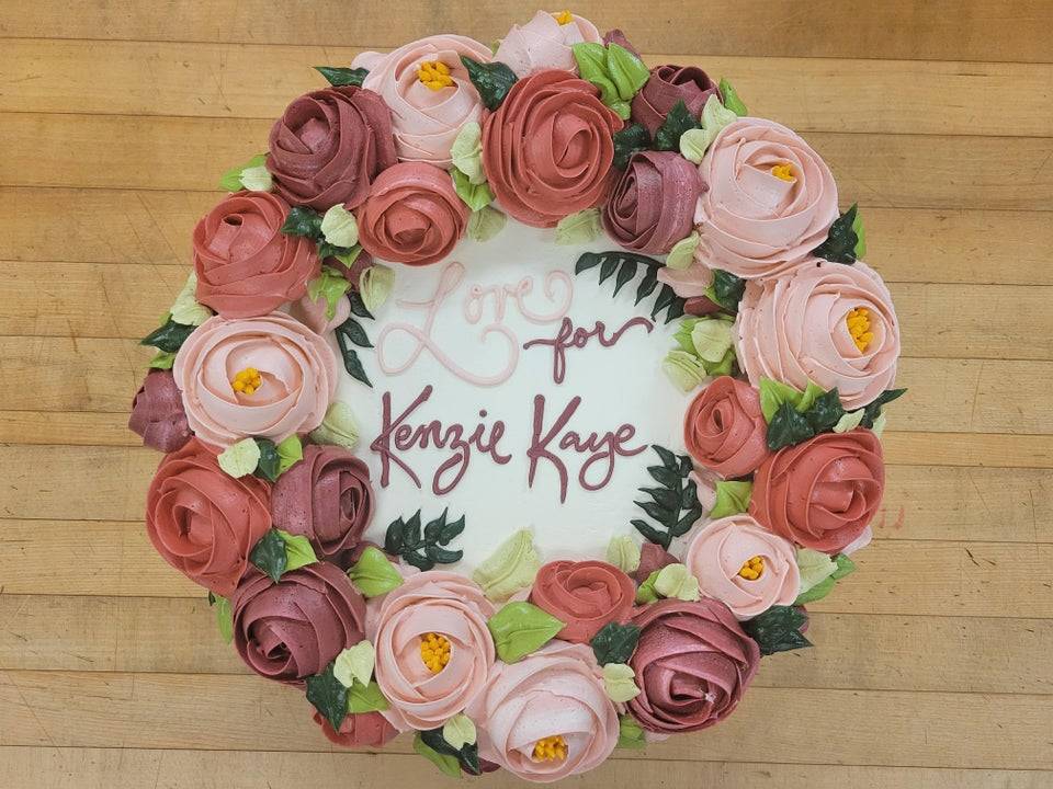 Cake that is shaped like a wreath and full of pink and red frosting roses