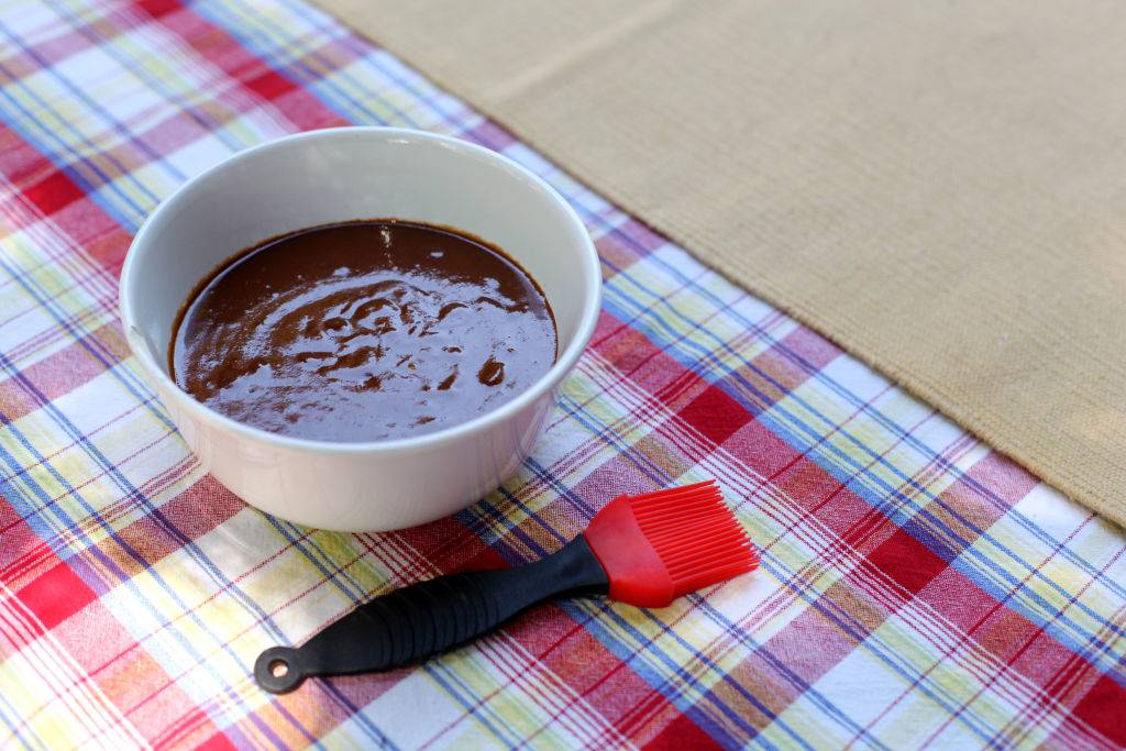 barbecue sauce in a white bowl on a plaid tablecloth