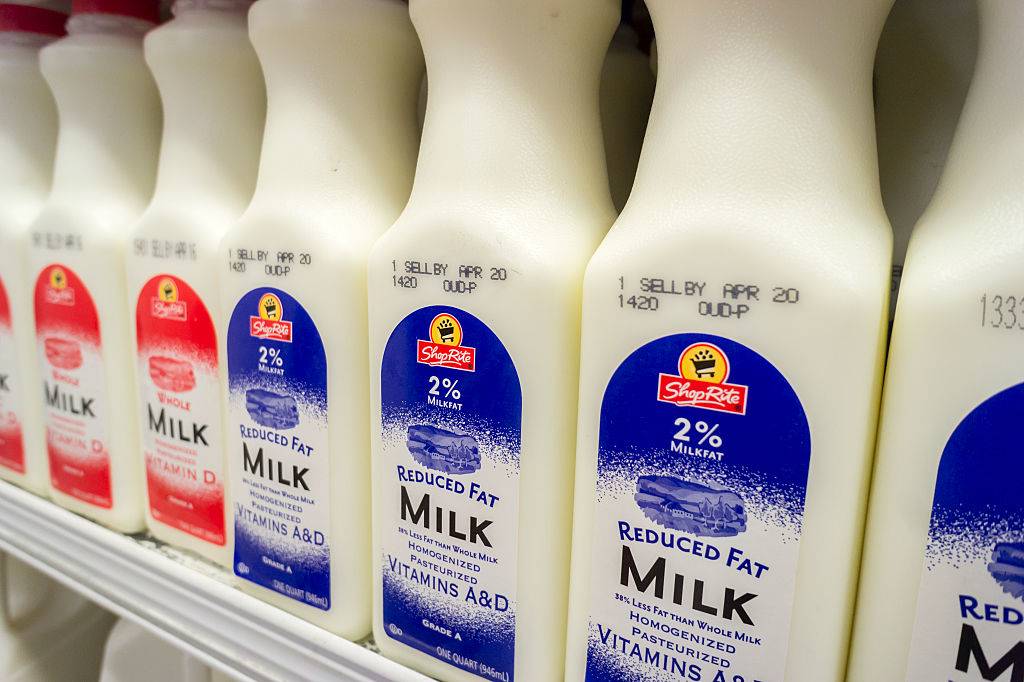 Containers of reduced fat and whole milk in a supermarket refrigerator