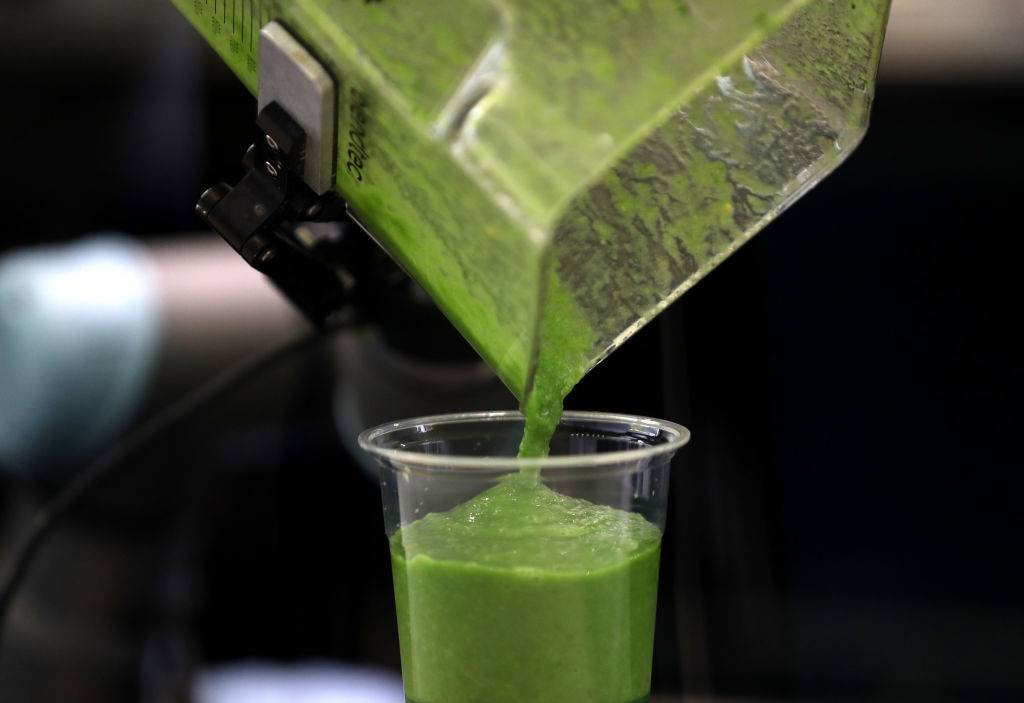 a green smoothie being poured into a cup