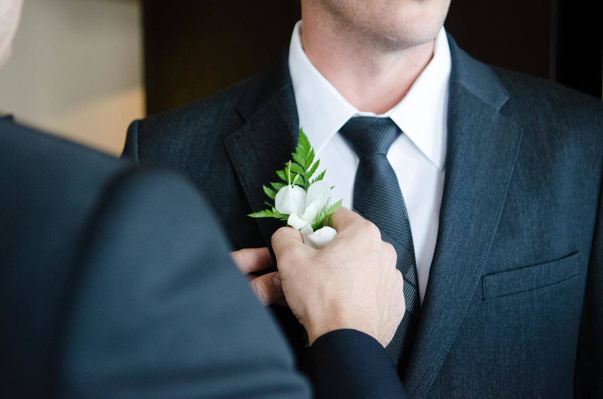 Man pinning boutonnière to another man's lapel