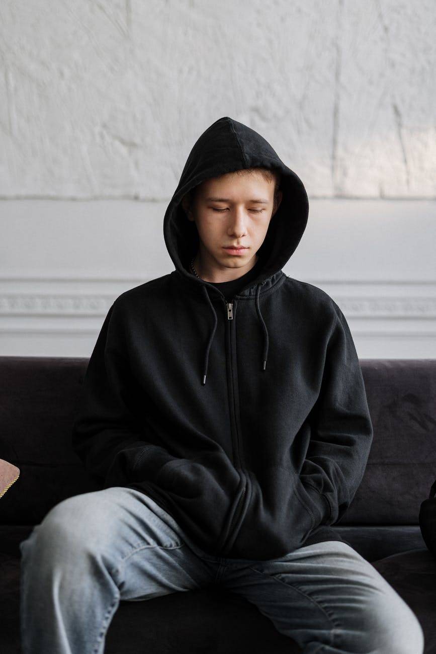 teenage boy wearing a black hoodie sitting down