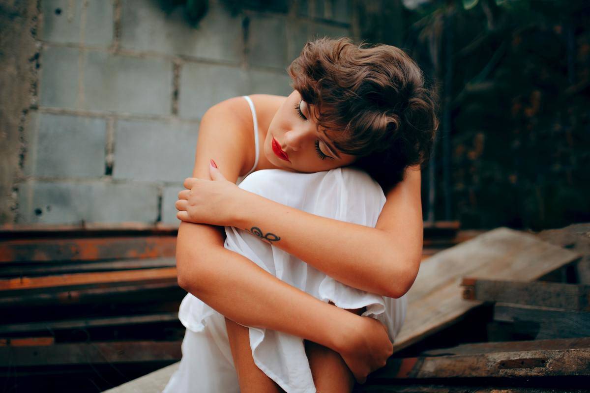 woman hugging in her knees in sadness