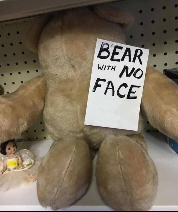 Stuffed teddy bear sitting with sign that says bear with no face