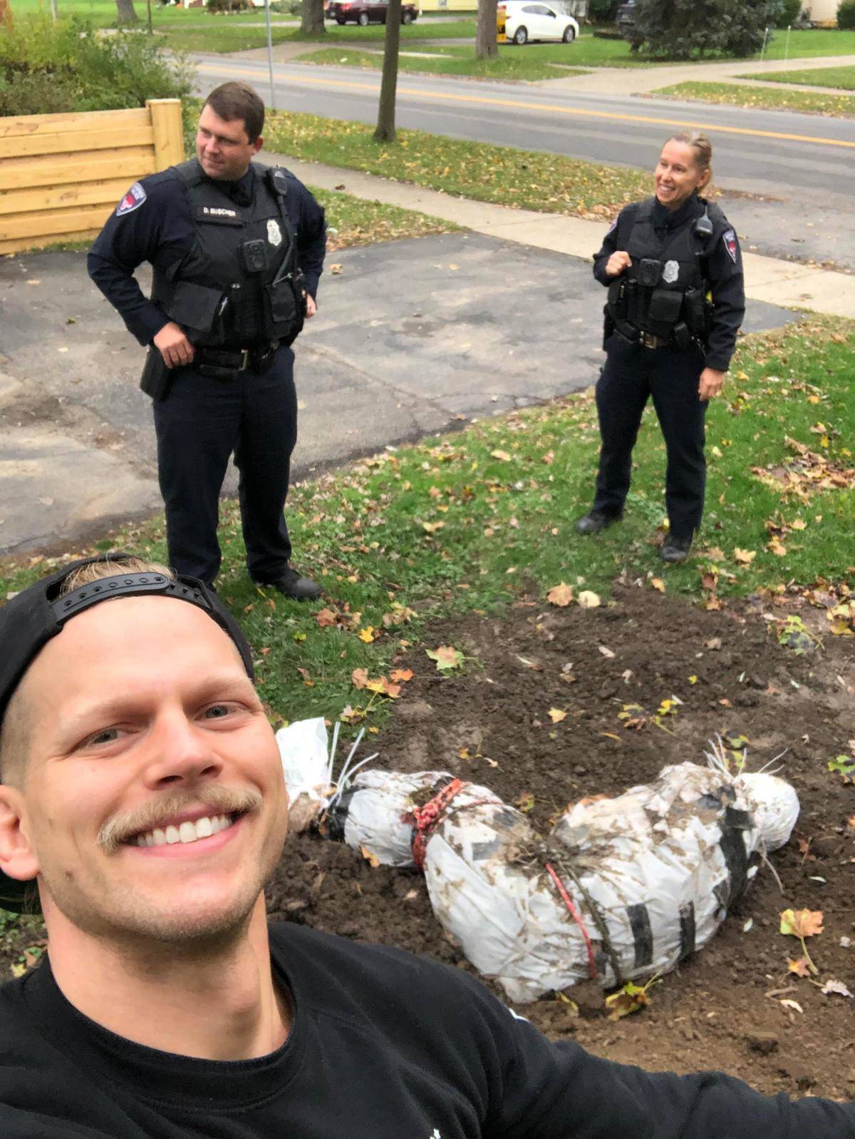Halloween decoration of wrapped-up body on front lawn draws police who smile for picture