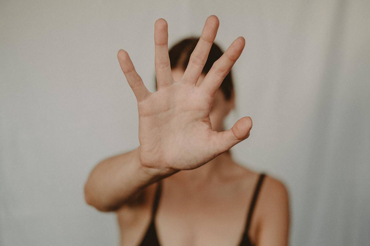 Woman holds out her hand so it covers her face
