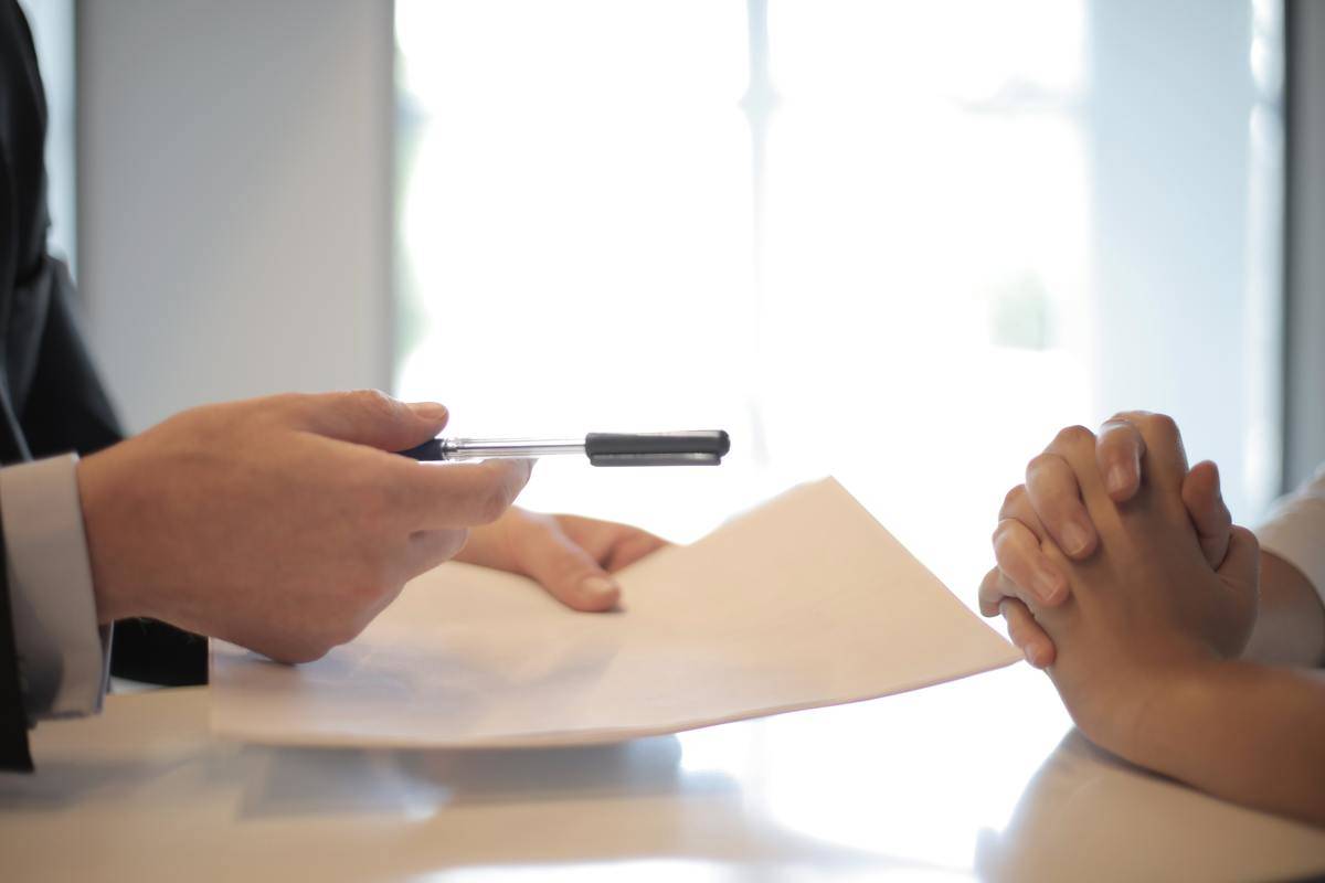 Man hands over a pen and a contract to a women