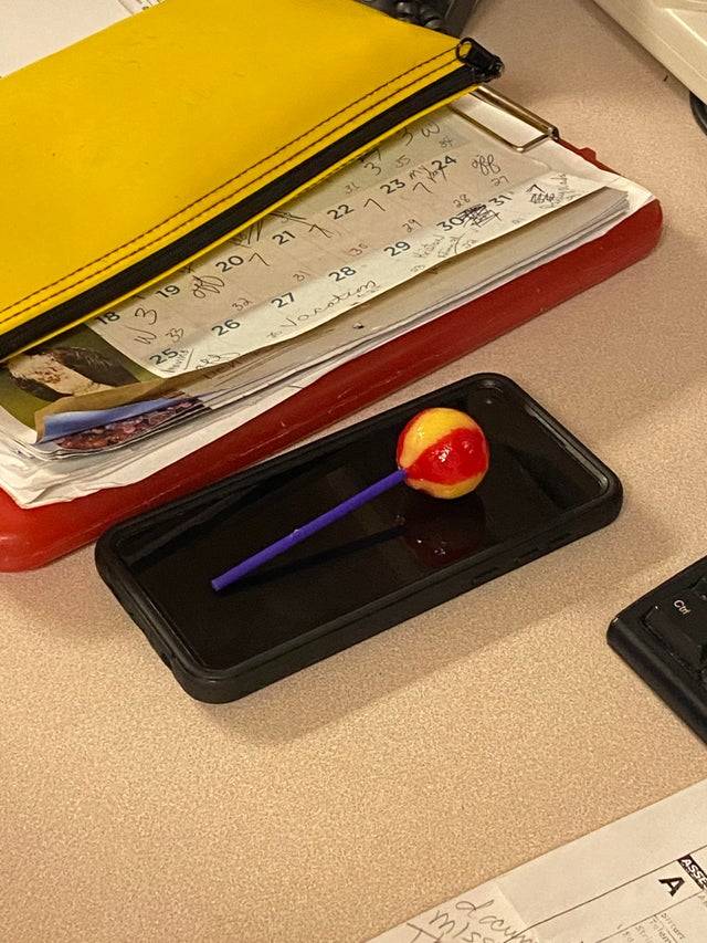 Coworker rests her lollipop on her phone screen during her shifts at a hospital
