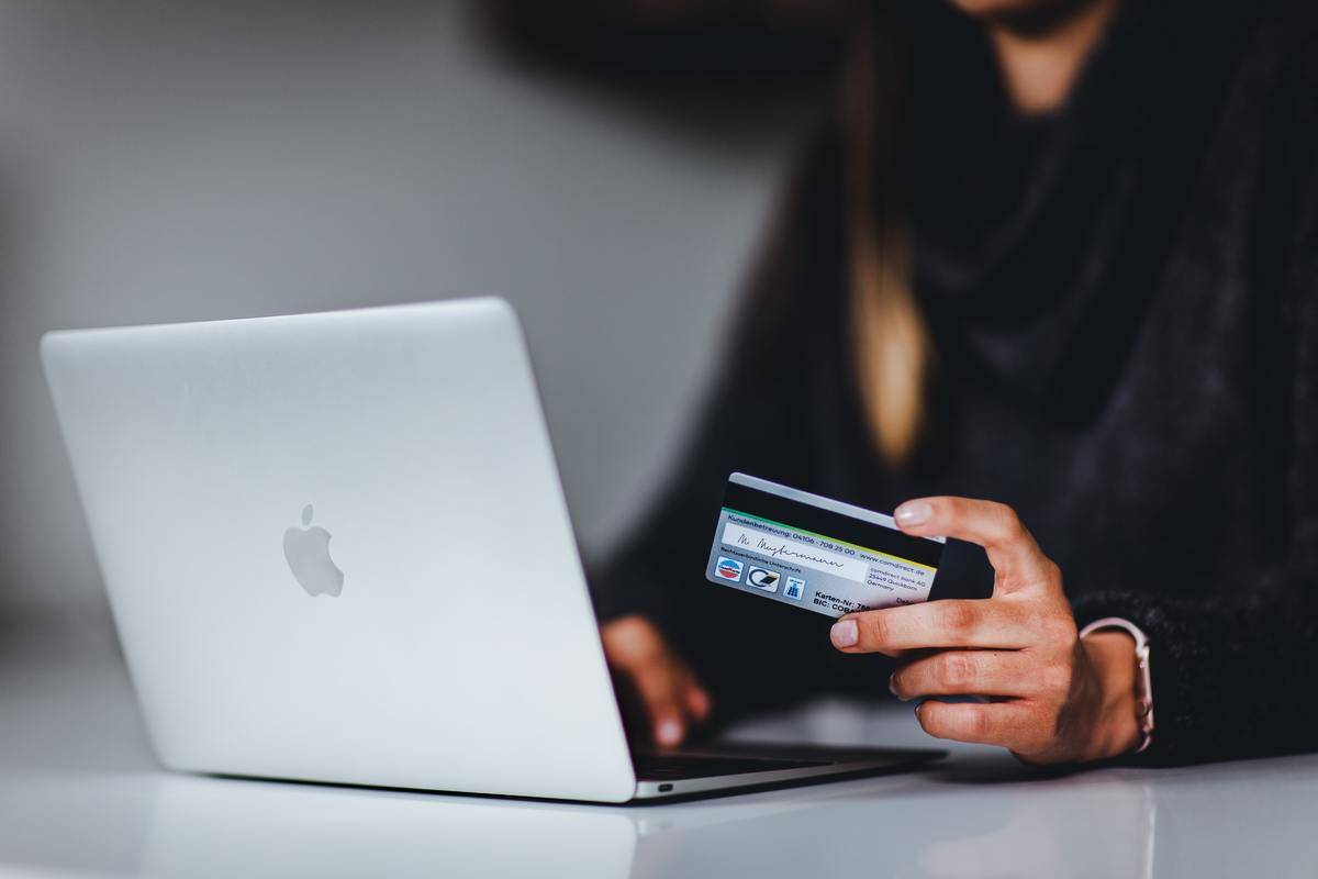 Woman holds a credit card while she uses her laptop to shop online