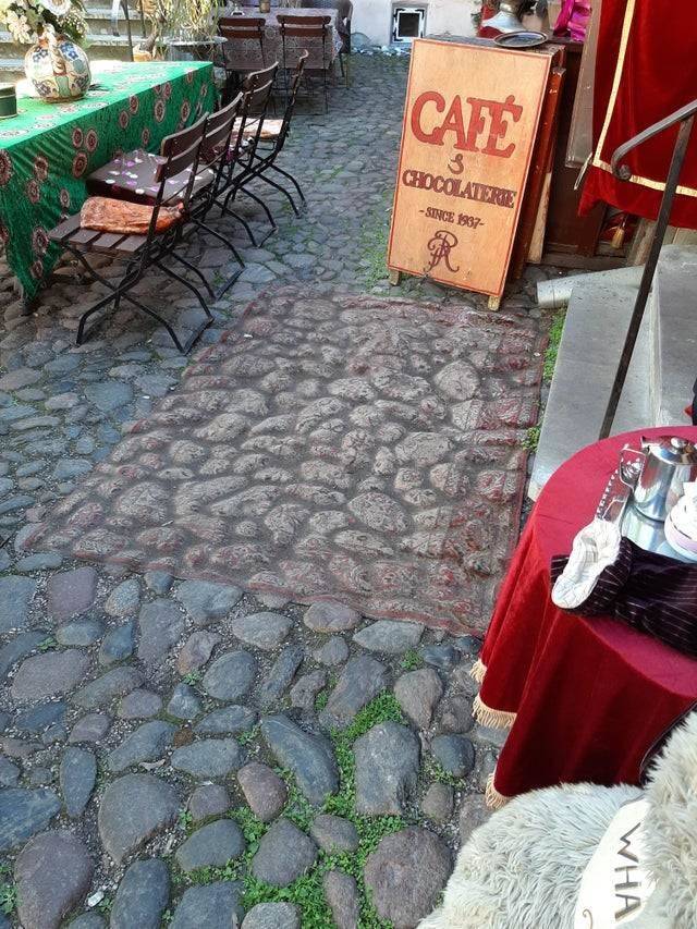 A rug laid over cobblestone is so worn down it appears to blend in with the stones