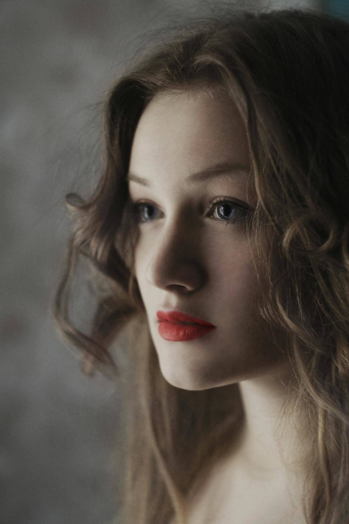 Woman with red lips and brown hair looks dramatically off camera